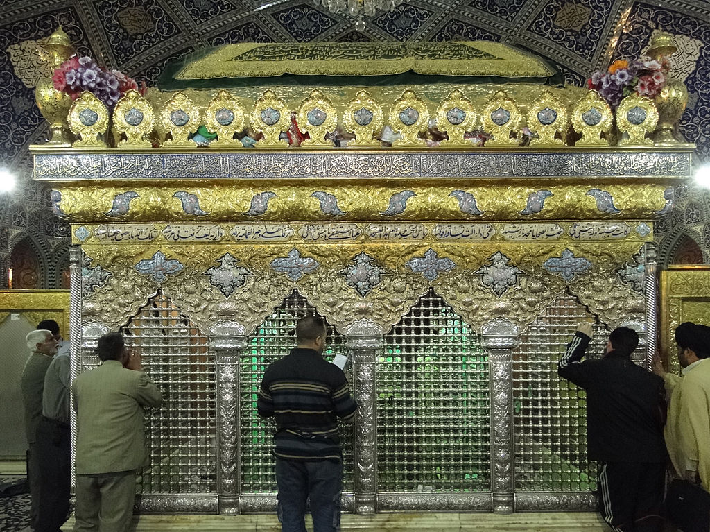 People stand praying at the silver and gold enclosure around Ruqayyah’s tomb.